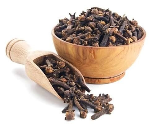 Chiodi di garofano interi biologici in una ciotola di legno con paletta dosatrice